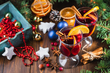 Hot Christmas drink made of wine, fragrant spices and fruits in a glass on a wooden rustic background with Christmas decorations. Holiday hot mulled wine or punch.