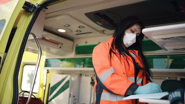 Young female paramedic fills documents inside ambulance vehicle
