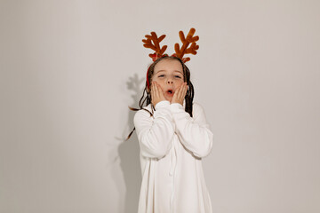 Little pretty charming kid in white dress and headgear decoration posing over isolated background