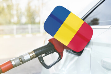 Flag of Romania on the car's fuel filler flap with gas pump nozzle in the tank.