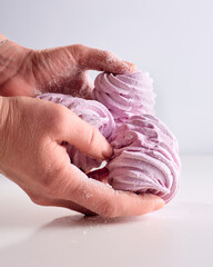 Fototapeta premium Pink tasty marshmallow in a women's hands isolated on a white background