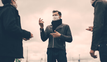 young people in protective masks talk standing at a safe distance