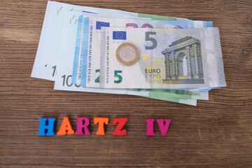 money, euro banknotes, black wallet, word in German Hartz IV made of colored letters lie on old...