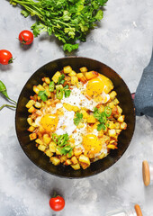 Potato hash with eggs and herbs for breakfast on concrete background