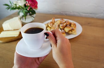 Cup of coffee in female hands, close-up. Homemade baked goods during quarantine. Homemade dessert...