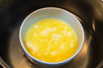 cooking sweet sponge cake at home - above view of melted butter in bowl in water bath at home kitchen