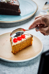 A slice of carrot cake being cut with a spoon from the load on a plate