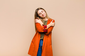 blonde woman feeling in love, smiling, cuddling and hugging self, staying single, being selfish and...