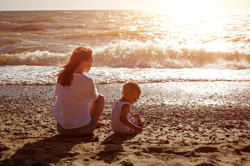 Fototapeta na wymiar Mom and son sit by the sea on a sunny summer day