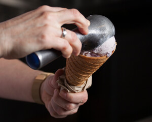 woman's hands scooping ice cream into a cone