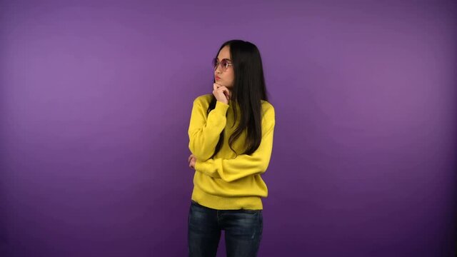 puzzled young asian woman in bright sunglasses looks left and right while making a choice. isolated purple background. 4K