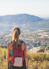 Blonde hiker girl looking back towards the mountainous horizon