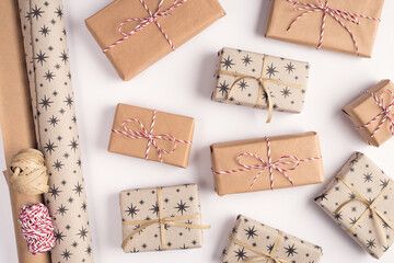 Preparing presents concept. Top above overhead close up view photo of pile lot stack of wrapped in kraft paper presents and rolls of wrapping paper with rope ribbon isolated white background