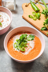 Red lentil tomato soup - delicious vegetarian food on concrte background. Healthy lunch