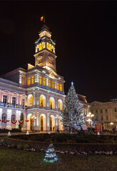 Fototapeta na wymiar Christmas tree and new year decorations in front of the town hall building, at night, in the city center of Arad, Romania