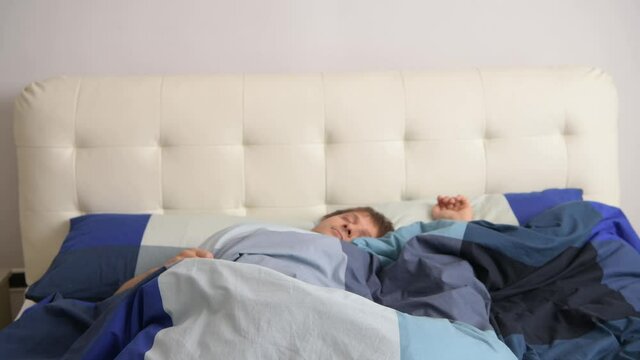 Man quietly sleeps in the bed and and breathes deeply in sleep