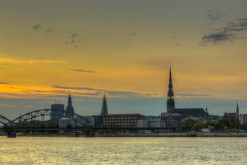 Fototapeta premium Night view on the illuminated riverside with reflection on the river in Riga