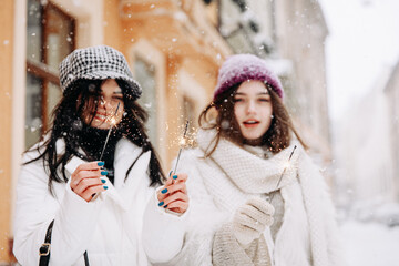 Cheerful females using sparklers during snowy weather