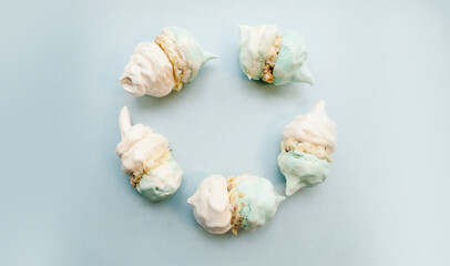 White-blue meringue with cream laid out in a circle. Blue background, place for text. Copy space.