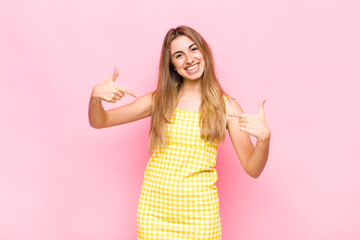 blonde woman looking proud, arrogant, happy, surprised and satisfied, pointing to self, feeling...