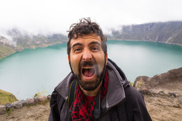 traveler man photographer screaming in spectacular landscape crater lake with fog quilotoa volcano ecuador latin america