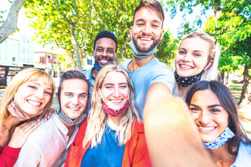 Multiracial friends taking happy selfie with open face masks after lockdown reopening - New normal...