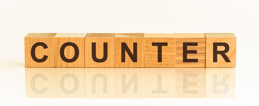 Wooden Blocks with the text: counter. The text is written in black letters and is reflected in the mirror surface of the table.