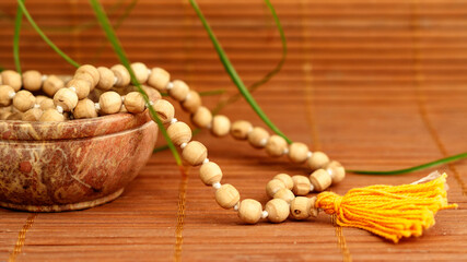 Bowl with buddhist prayer beads and green plant on wooden background with copy space. Essential...