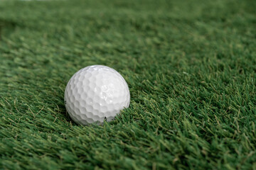 Golf ball on green artificial grass, top view with space for text - macro, selective focus, space for text
