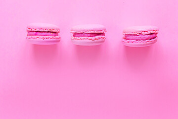 Sweet almond pink macaron or macaroon dessert cake isolated on trendy pink pastel background. French sweet cookie. Minimal food bakery concept. Flat lay top view, copy space