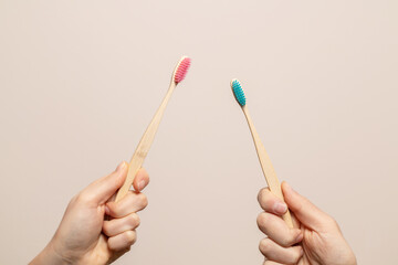 Pink and blue bamboo toothbrush in hands