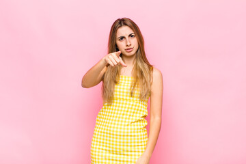 blonde woman pointing at camera with an angry aggressive expression looking like a furious, crazy...