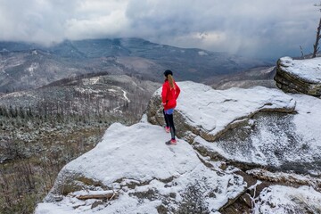 Drone view on a athlete runner standing on a rock admiring beautiful mountain views.