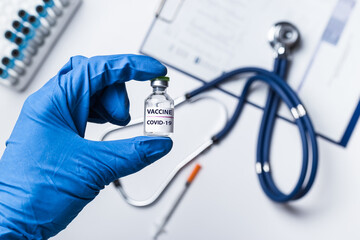 Doctor, scientist or nurse's hand in blue gloves holding vial coronavirus vaccine shot for diseases outbreak vaccination, medicine and drug concept