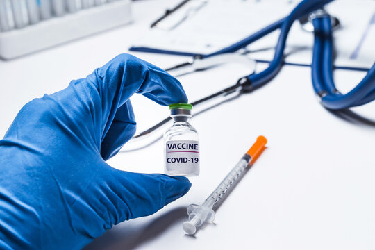 Doctor, scientist or nurse's hand in blue gloves holding vial coronavirus vaccine shot for diseases outbreak vaccination, medicine and drug concept