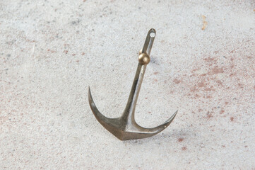 Brass anchor on concrete background.