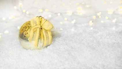Fototapeta na wymiar Christmas balloon with a Golden bow in the snow on an abstract background