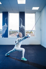 Fototapeta na wymiar Child in a fencing costume and mask, with a sword, fencing school