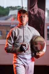 A guy in a fencing suit with a sword in his hand, neon light. A young model trains and trains in movement, action. Sports, youth, healthy lifestyle.