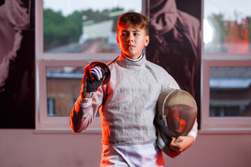 A guy in a fencing suit with a sword in his hand, neon light. A young model trains and trains in...