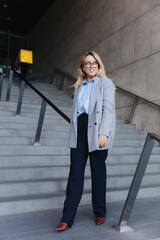 Stylish business woman standing on stairs outdoors