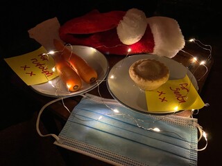 covid-19 Christmas eve, santa hat with face mask and for Santa note with mince pie and carrots for...