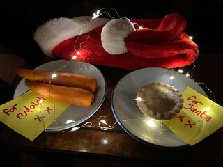 covid-19 Christmas eve, santa hat with face mask and for Santa note with mince pie and carrots for...