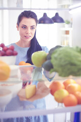 Obraz premium Smiling woman taking a fresh fruit out of the fridge, healthy food concept