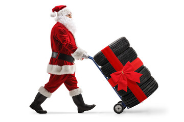 Santa claus pushing car tires tied with a red bow on a hand truck