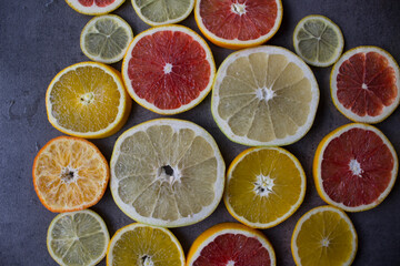Naklejka na ściany i meble Juicy citrus fruits slices top view photo. Colorful background made of fresh oranges, grapefruits, limes and lemons. Healthy eating concept. 