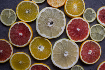 Fototapeta na wymiar Colorful background made of red orange, lime, grapefruit and lemon slices. Beautiful colors of fruit texture. Citrus close up photo. Healthy eating concept. 