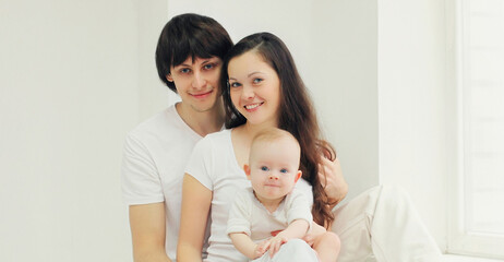 Family portrait of happy mother, father and baby over a white background