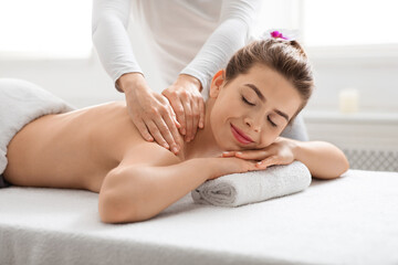Obraz na płótnie Canvas Joyful young lady getting back massage at spa