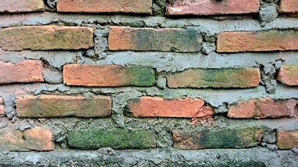 the arrangement of red bricks on the old and mossy walls of the building